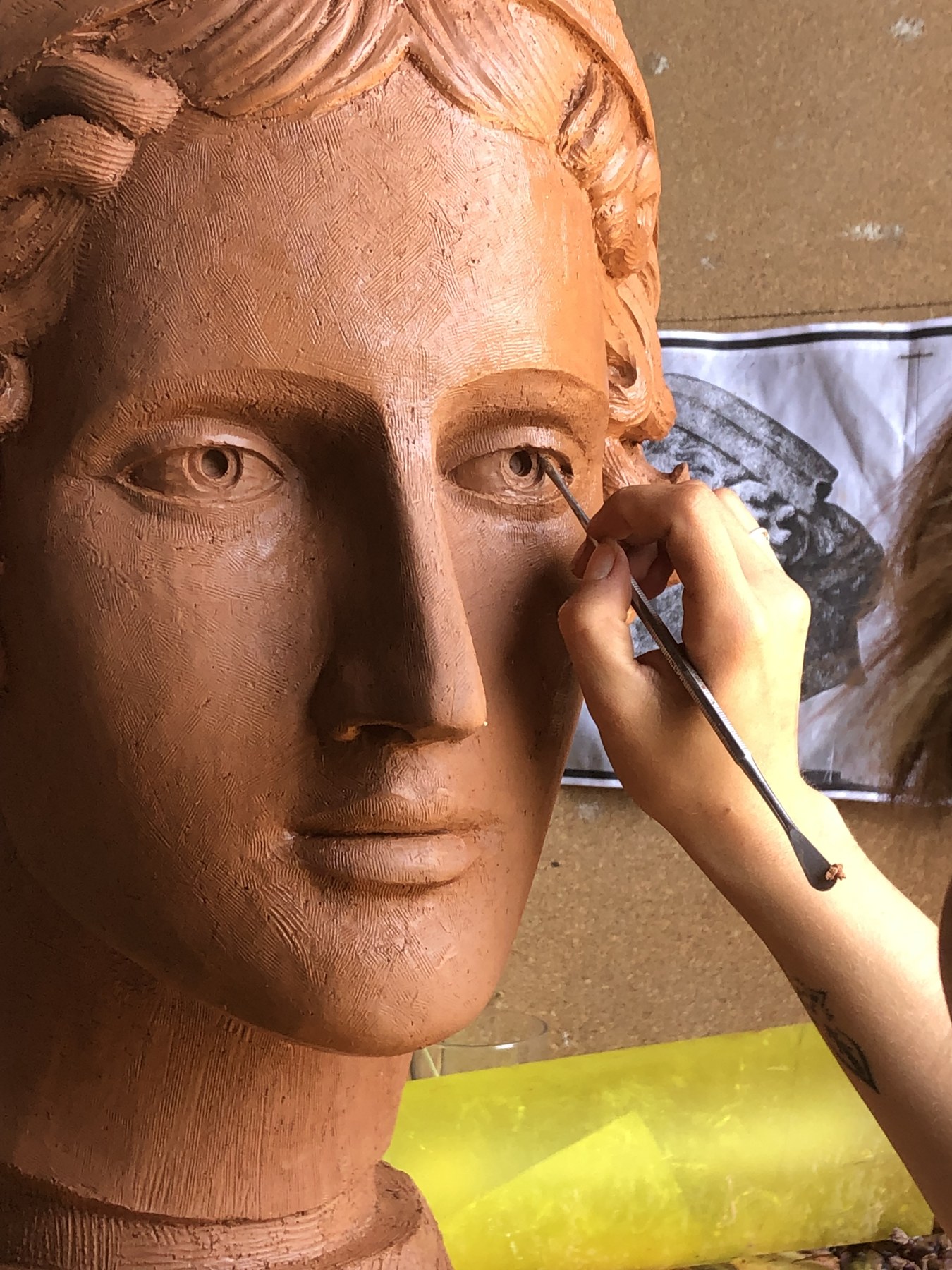 Travail du détail sur un visage modelé en argile.