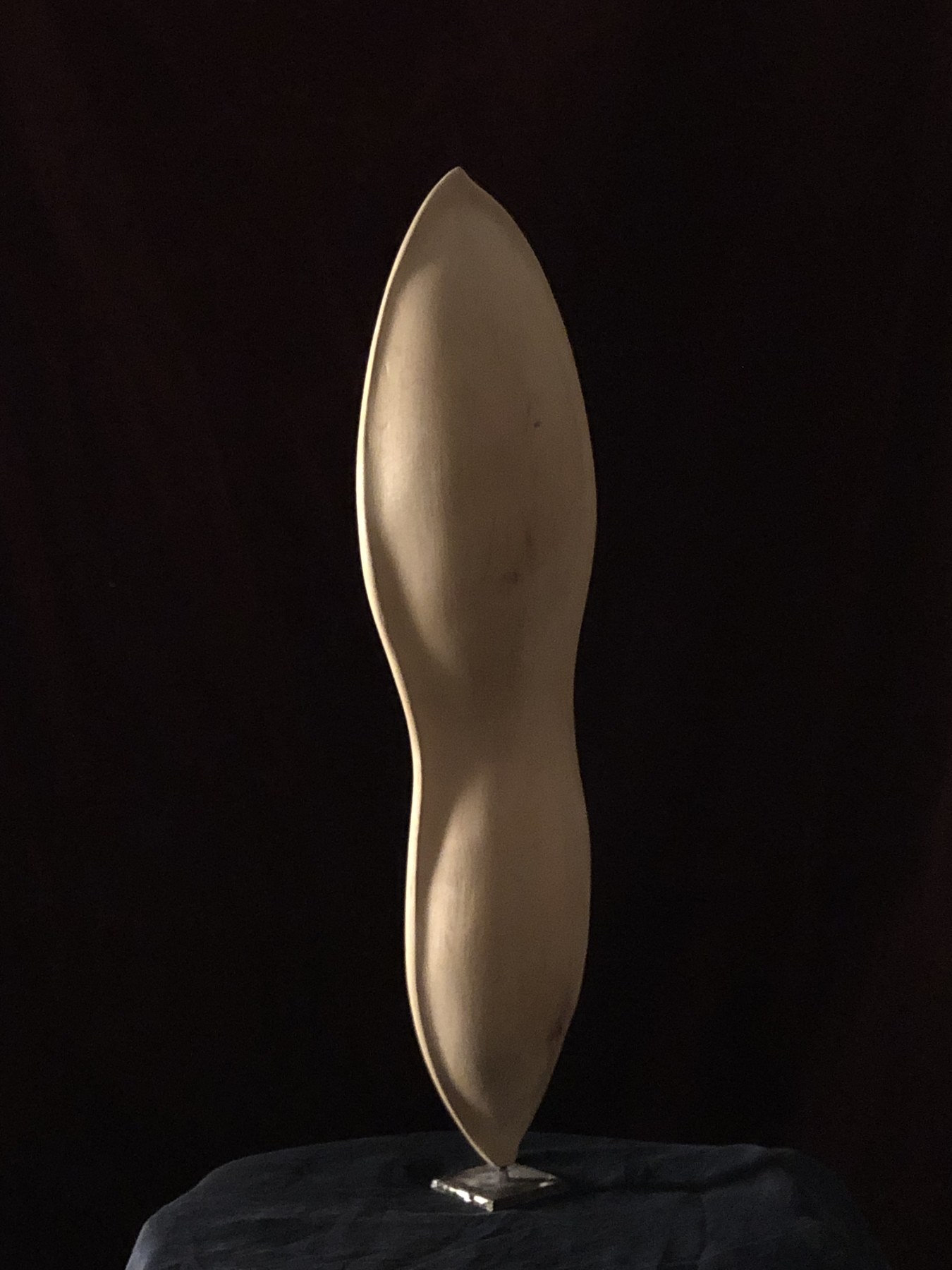 Sculpture élancée présentée sur un socle.